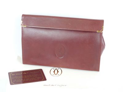 pochette en cuir marron avec des finitions dorées et une étiquette sur fond blanc