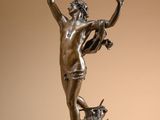 bronze statue of a man on a rock with a cow