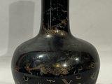 un vase noir orné de motifs dorés sur fond blanc
