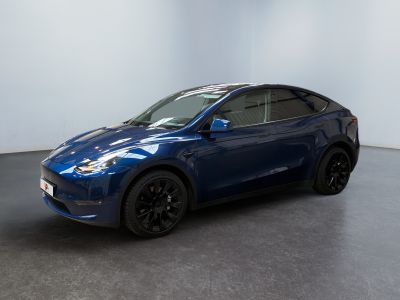 un SUV Tesla bleu garé dans une pièce blanche