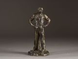 bronze statue of a man standing on a rock with his hands on his hips