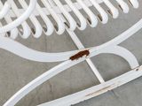 a white rocking chair with a rusted seat on it