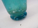 a blue glass vase sitting on top of a white table