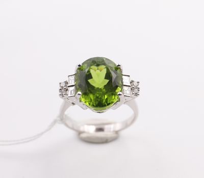 a green tourmaline and diamond ring on a white background