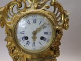 a gold clock with roman numerals on the face