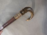 a hand holding a wooden stick with a metal handle