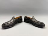 une paire de mocassins noirs posés sur une surface blanche