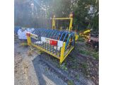 une machine jaune et noire posée au milieu d'un champ de terre battue