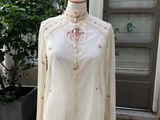 une chemise blanche ornée de fleurs roses, posée sur un mannequin