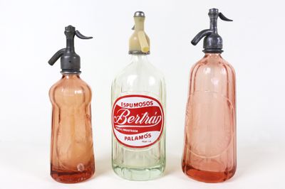 trois flacons contenant du savon et de la lotion, posés sur une surface blanche