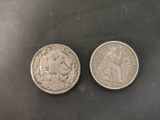 two silver coins sitting side by side on a black surface