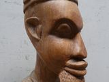 une statue en bois représentant un homme moustachu