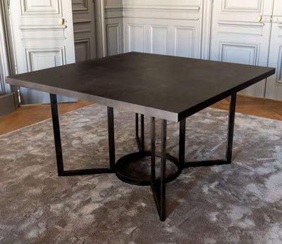 une table noire avec un piètement en métal dans une pièce