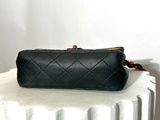 black quilted leather purse on a white pedestal against a white wall