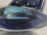 a blue glass vase with a black base on a table