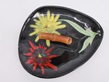 a black plate with a flower and a bamboo stick on it