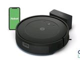 un aspirateur robot noir avec un téléphone à côté