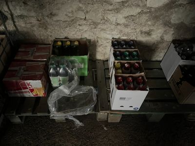 many boxes of soda sitting on a pallet next to a wall