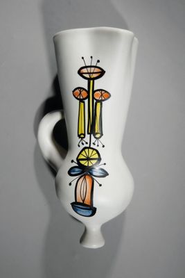 un vase blanc orné d'un motif, accroché au mur