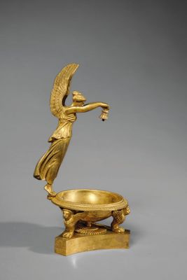 une figurine en or représentant un ange tenant un bol, posée sur un socle