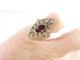 an image of a woman ' s hand holding a ring with a red stone
