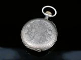 a silver pocket watch sitting on a black surface