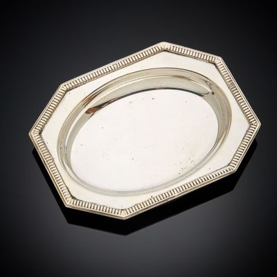 une assiette ancienne en argent, avec un bord perlé sur un fond noir