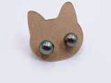 a cat shaped earring with green eyes on it
