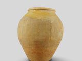 a yellow vase that is sitting on a white surface