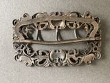 a silver buckle with a design on it on a table