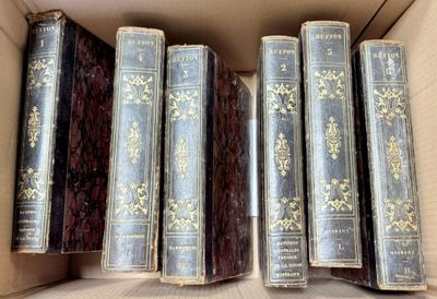 several old books are in a cardboard box on a table
