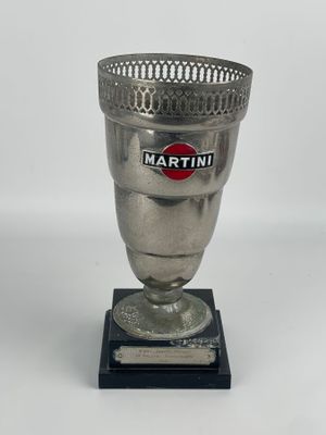 tasse argentée sur un socle noir, ornée du logo Martini