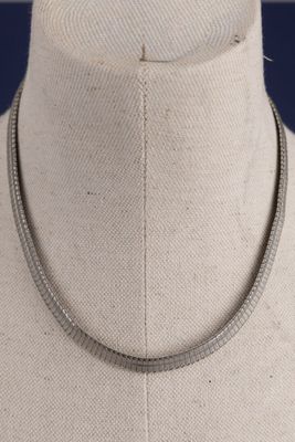 collier en métal argenté, au motif incurvé, posé sur le cou d'un mannequin