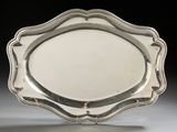 silver plate with scalloped edge on stand against black background