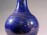 a blue vase with gold designs on it sitting on a table