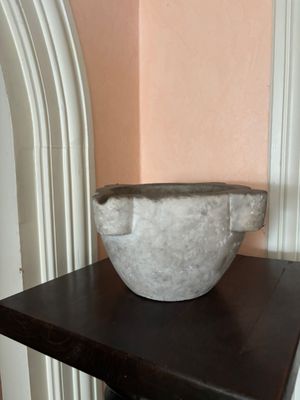 a marble bowl sitting on a table in the corner of a room