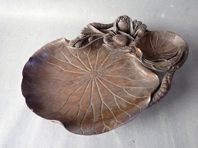 une assiette en argent sur laquelle est représentée une grenouille assise sur une feuille