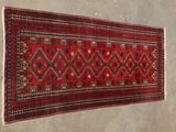 un vieux tapis rouge et noir accroché au mur