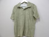 green shirt hanging on a hanger against a white wall