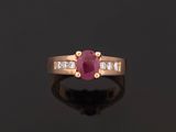 an oval ruby and diamond ring on a black surface