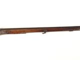 un vieux fusil accroché au mur, à côté d'un mur blanc