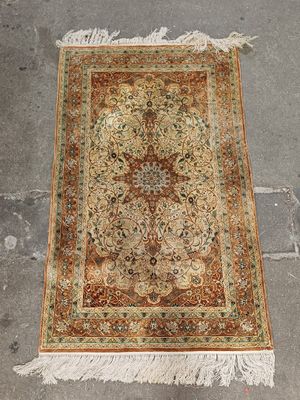 un tapis persan ancien posé à même le sol, avec des franges