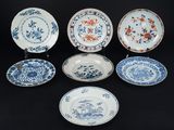six assiettes bleues et blanches ornées de motifs floraux sur fond noir