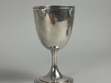 un gobelet en argent posé sur une surface blanche