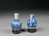 two blue and white vases sitting on top of a wooden stand