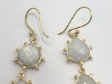 gold plated earrings with white stones on them on a white surface