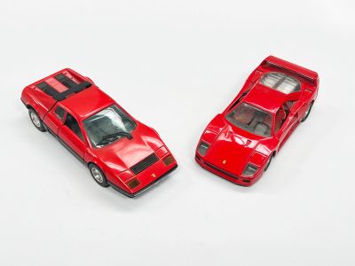 deux petites voitures rouges posées l'une à côté de l'autre sur une surface blanche
