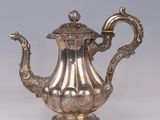 an antique silver teapot with a handle on a white surface