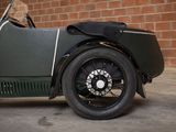 a green vintage car parked in front of a brick wall