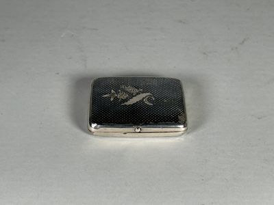 un petit étui à cigarettes en argent posé sur une surface blanche